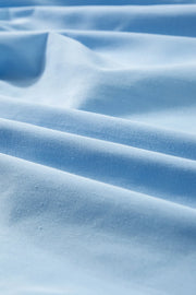 Light blue poplin fabric with soft folds, showing texture detail.