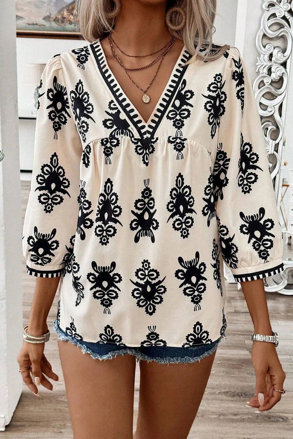Ivory embroidered V-neck blouse with black contrast trim and 3/4 sleeves.