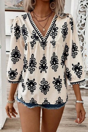 Ivory embroidered V-neck blouse with black contrast trim and 3/4 sleeves.
