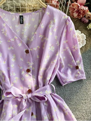 Violet floral V-neck midi dress with button-down front and belted waist.