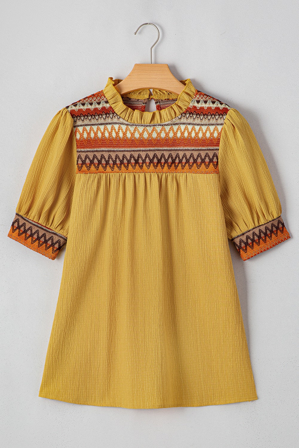 Mustard blouse with embroidered yoke, ruffled neckline, and puff sleeves.