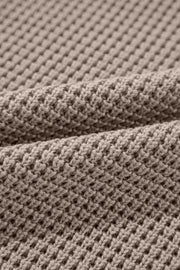 Mocha knit turtleneck sweater with checkerboard and stripe sleeves.