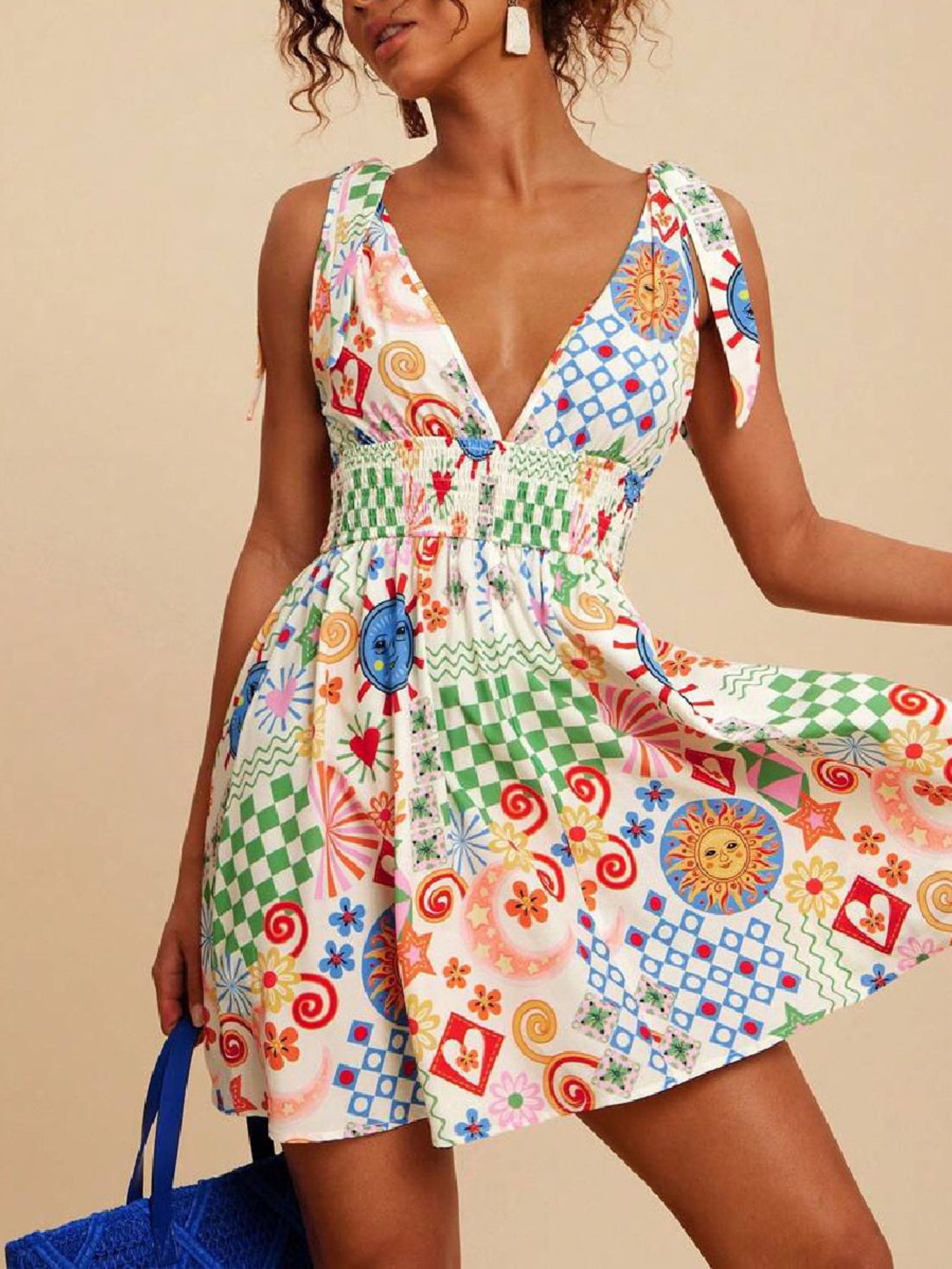 Playful printed mini dress with tied straps, V-neck, smocked waist, and colorful sun and checkered patterns.