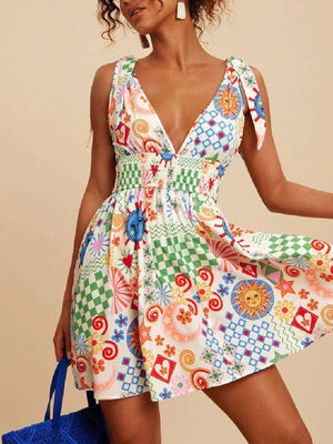 Playful printed mini dress with tied straps, V-neck, smocked waist, and colorful sun and checkered patterns.