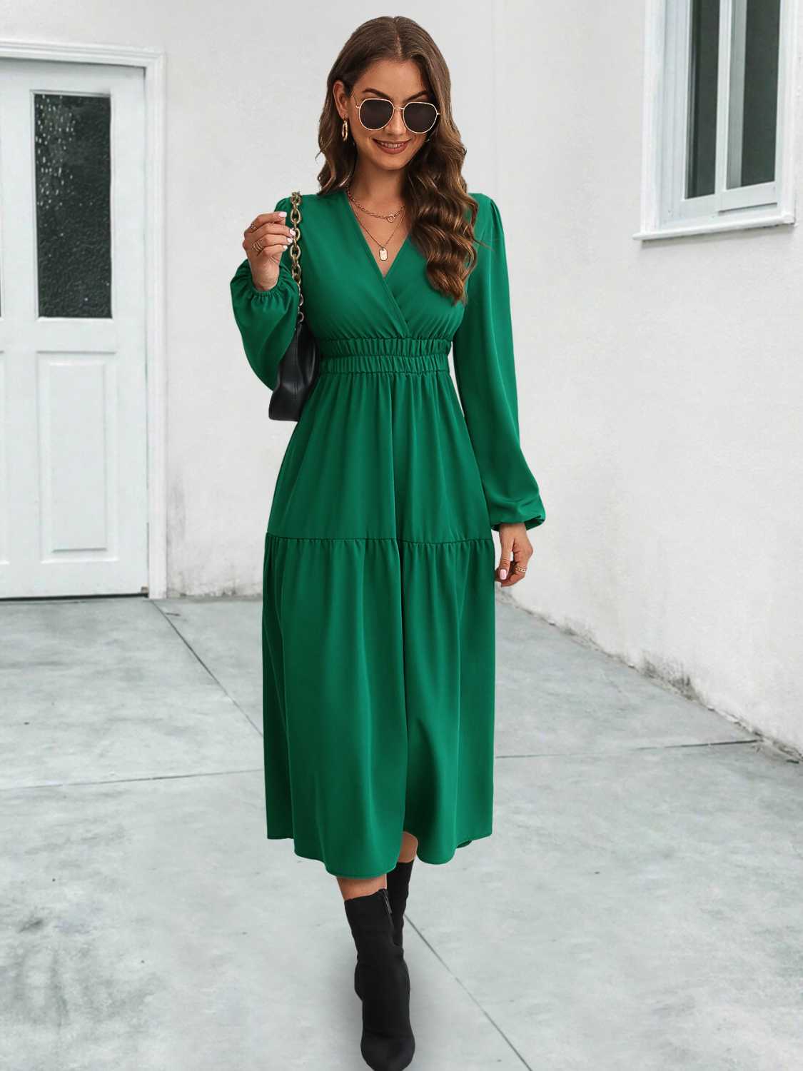 Dark green tiered midi dress with gathered waistline and long sleeves.