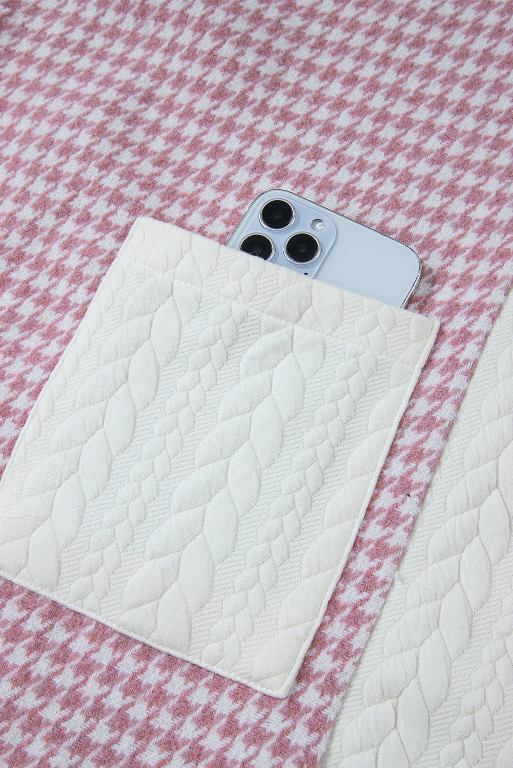 Panelled houndstooth shacket in dusty pink with quilted pocket detail and a phone.