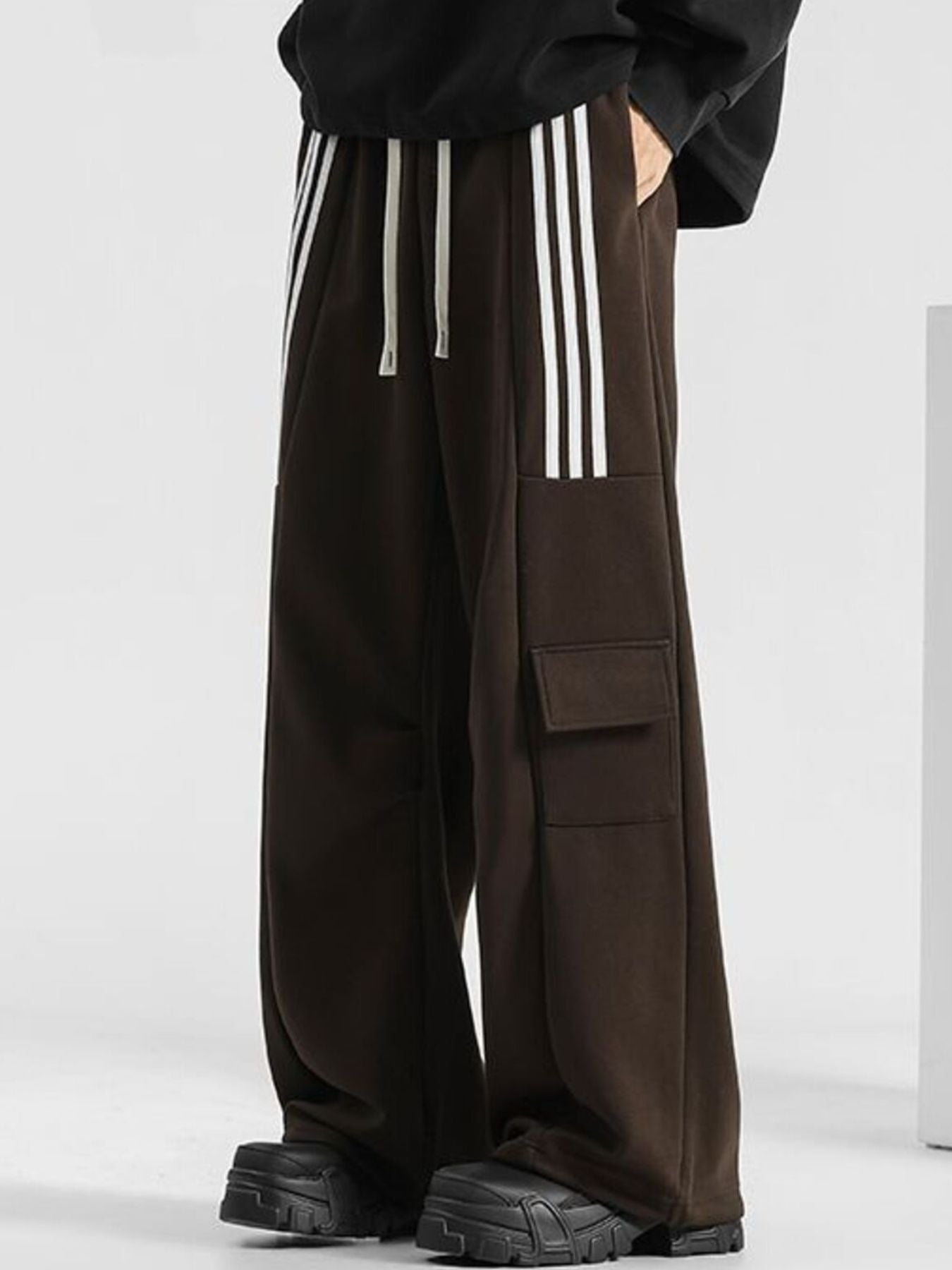 Men's brown loose-fit sweatpants with white side stripes and cargo pockets.