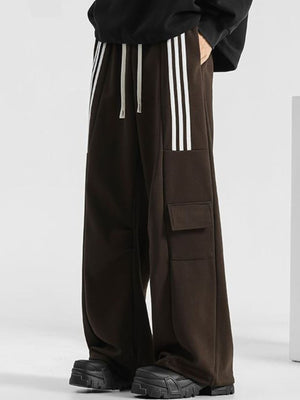 Men's brown loose-fit sweatpants with white side stripes and cargo pockets.