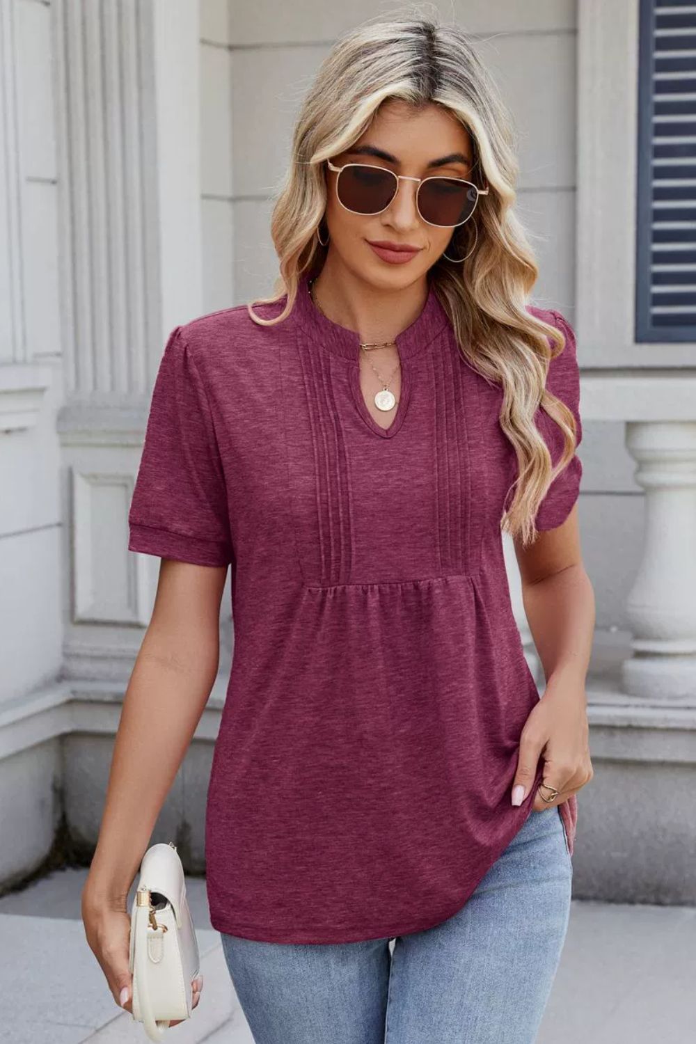 Plum purple short sleeve blouse with keyhole neckline and pleated yoke detail.