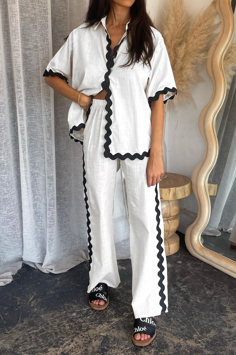 White linen co-ord set with black scalloped trim on shirt and pants.