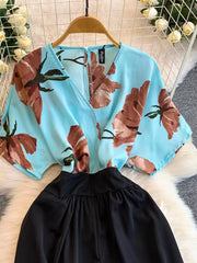 Blue abstract floral print wide-leg romper with black gathered waist and pockets.