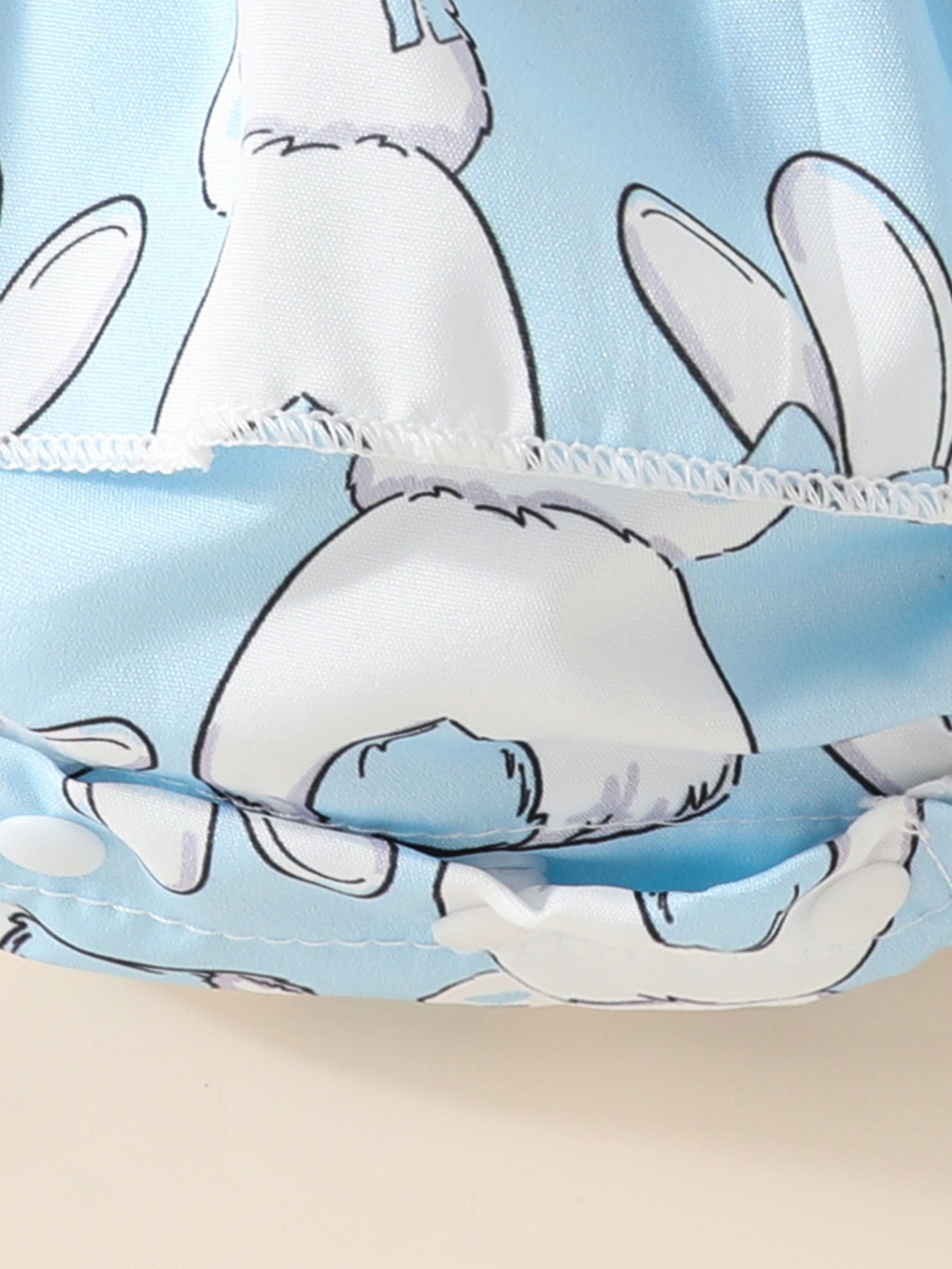 Sky blue baby dress with white bunny print and ruffled hem detail.