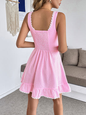 Pink gingham mini dress with sweetheart neckline, smocked bodice, lace trim and ruffled hem.