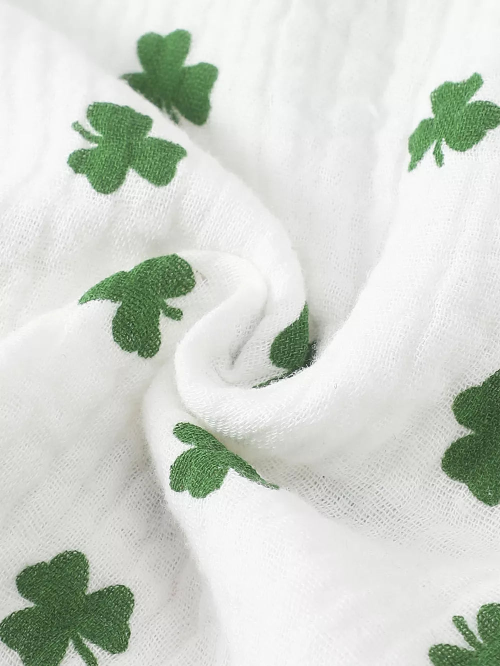 White cotton baby set with green shamrock print and ruffle detail.