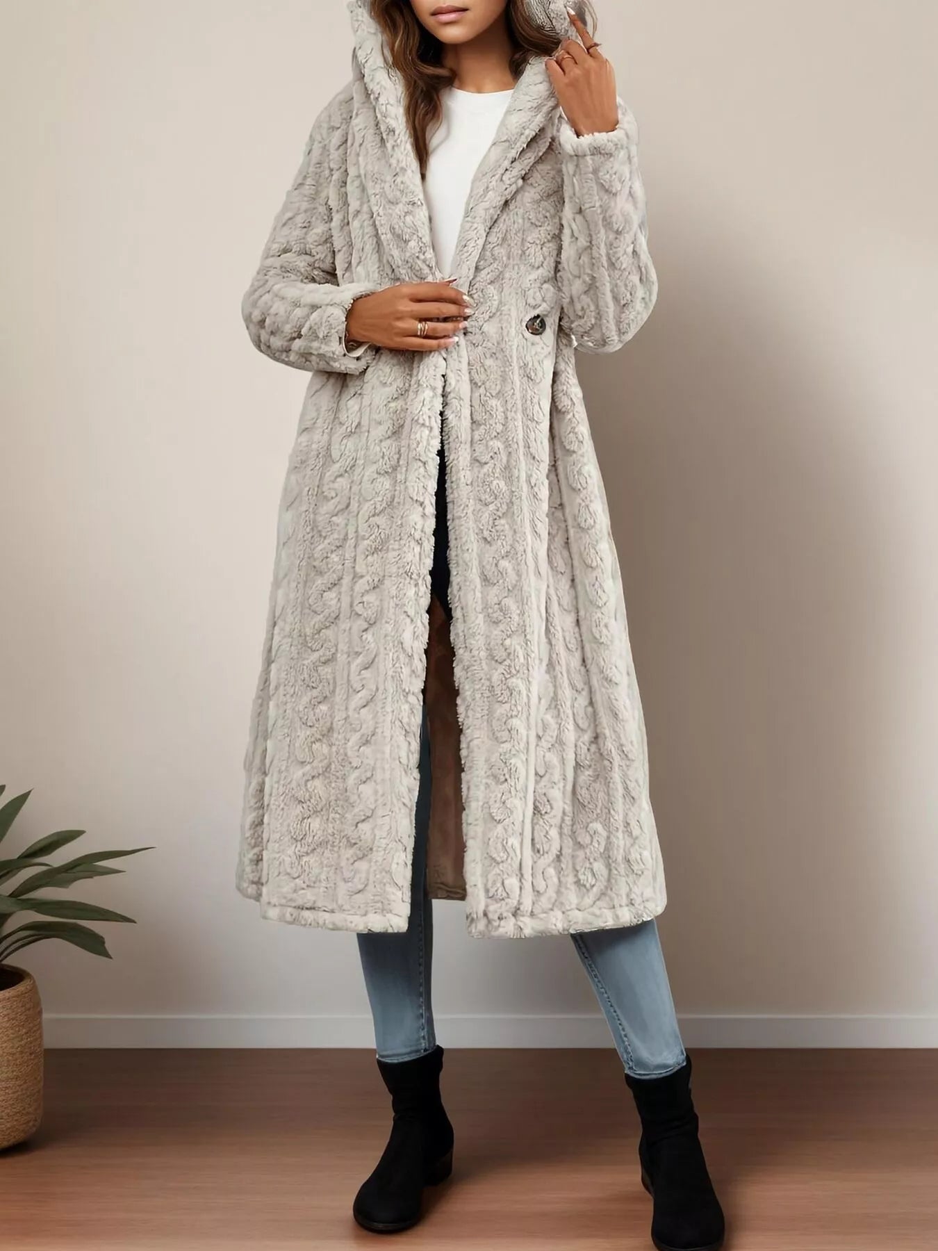 Gray hooded longline coat with cable knit texture and button closure.