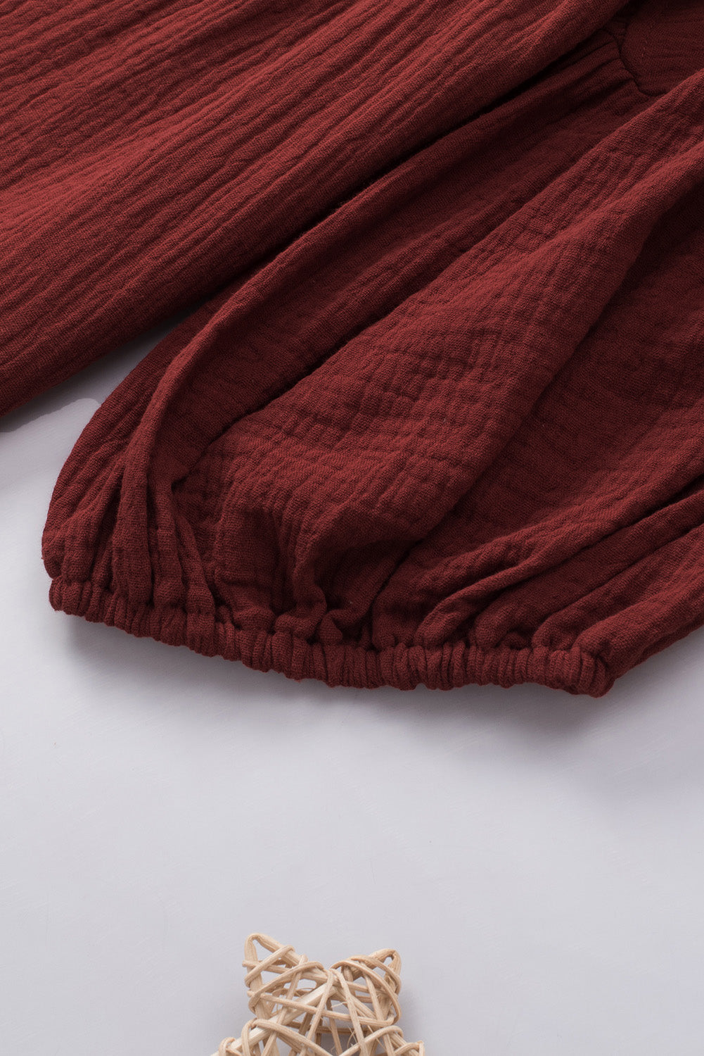 Textured gauze blouse in wine with gathered sleeves and elastic hem detail.
