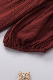 Textured gauze blouse in wine with gathered sleeves and elastic hem detail.