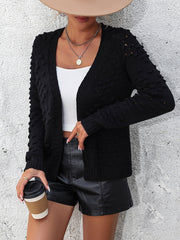Black acrylic cardigan with textured sleeves and open front, styled with a white top and black shorts.