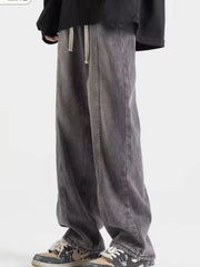 Men's dark gray distressed oversized fit jeans with drawstring waist and wide leg.