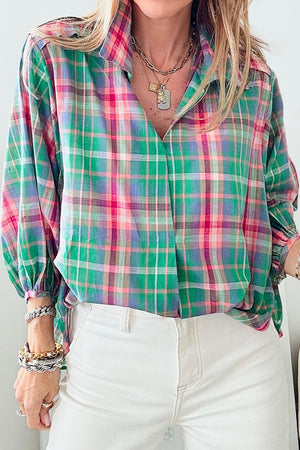 Voluminous plaid blouse with gathered sleeves and a V-neck, styled with white pants.