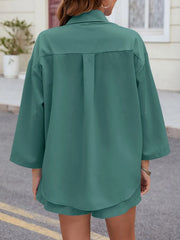 Teal oversized button-down shirt with pleats on back, paired with pleated shorts.