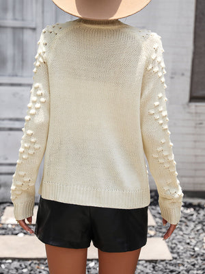 Cream acrylic cardigan with textured bobble sleeves and ribbed cuffs.