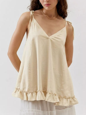 Ivory camisole with tie straps, V-neck, and ruffled hem detail.