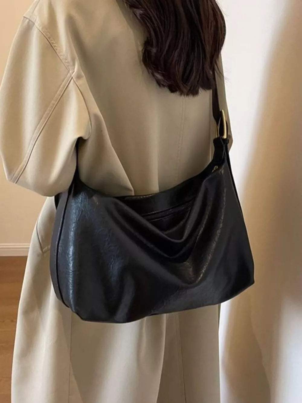 Black leather shoulder bag with adjustable strap and gold buckle detail