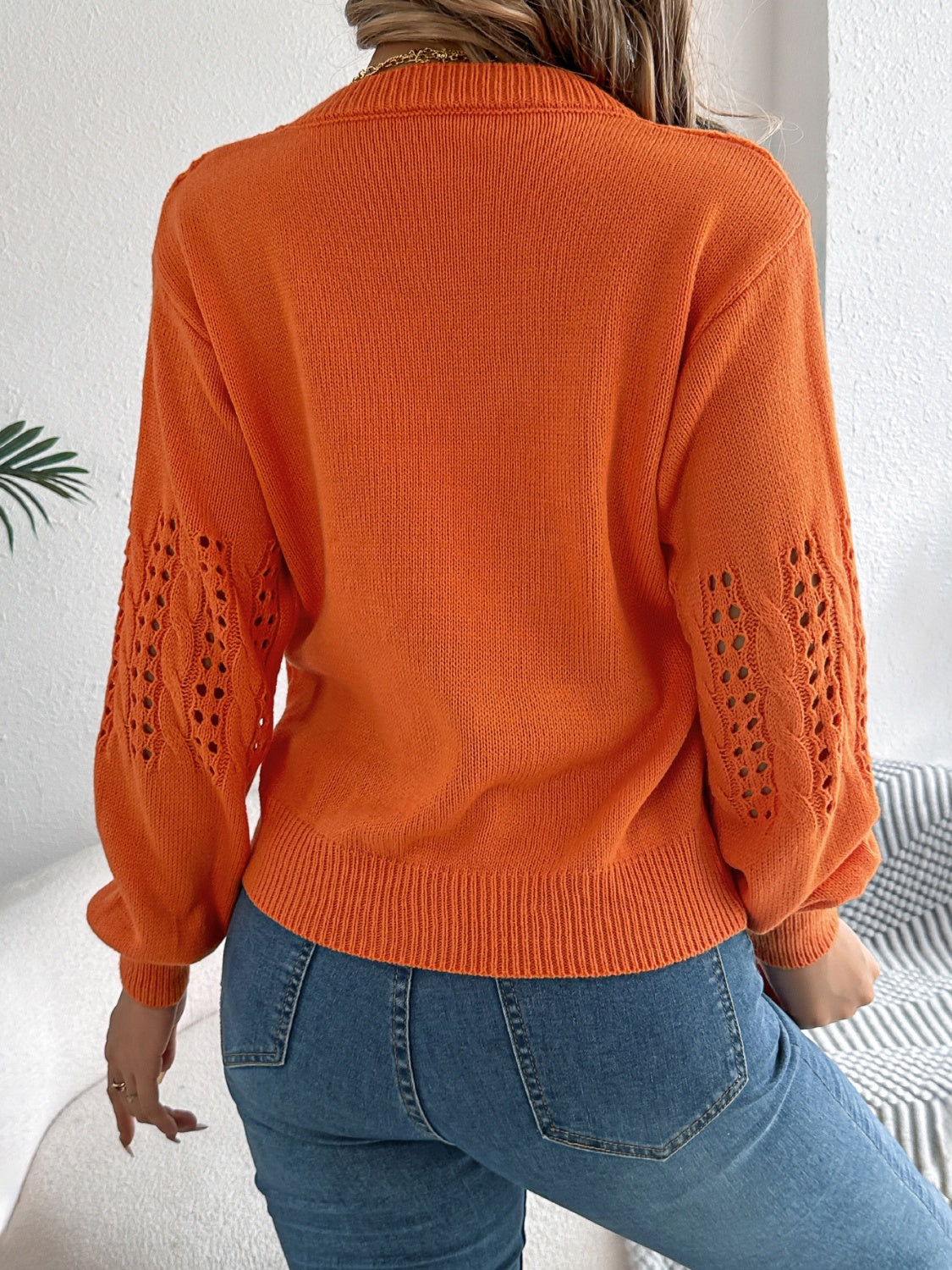 Orange knit sweater with openwork cable knit sleeves and crew neck.