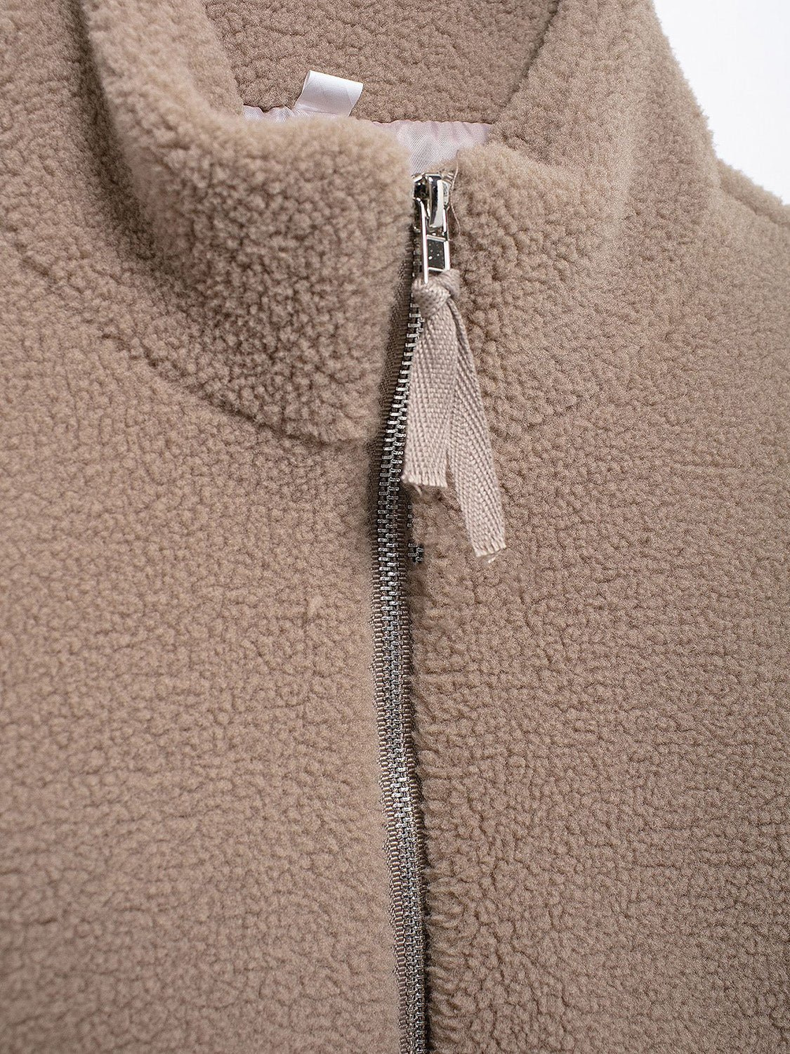 Tan sherpa stand-collar jacket with full zip and fabric pull tab.