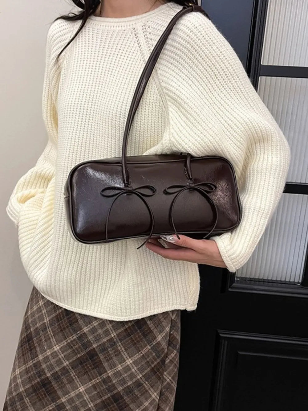 Chocolate patent leather shoulder bag with double bow detail.