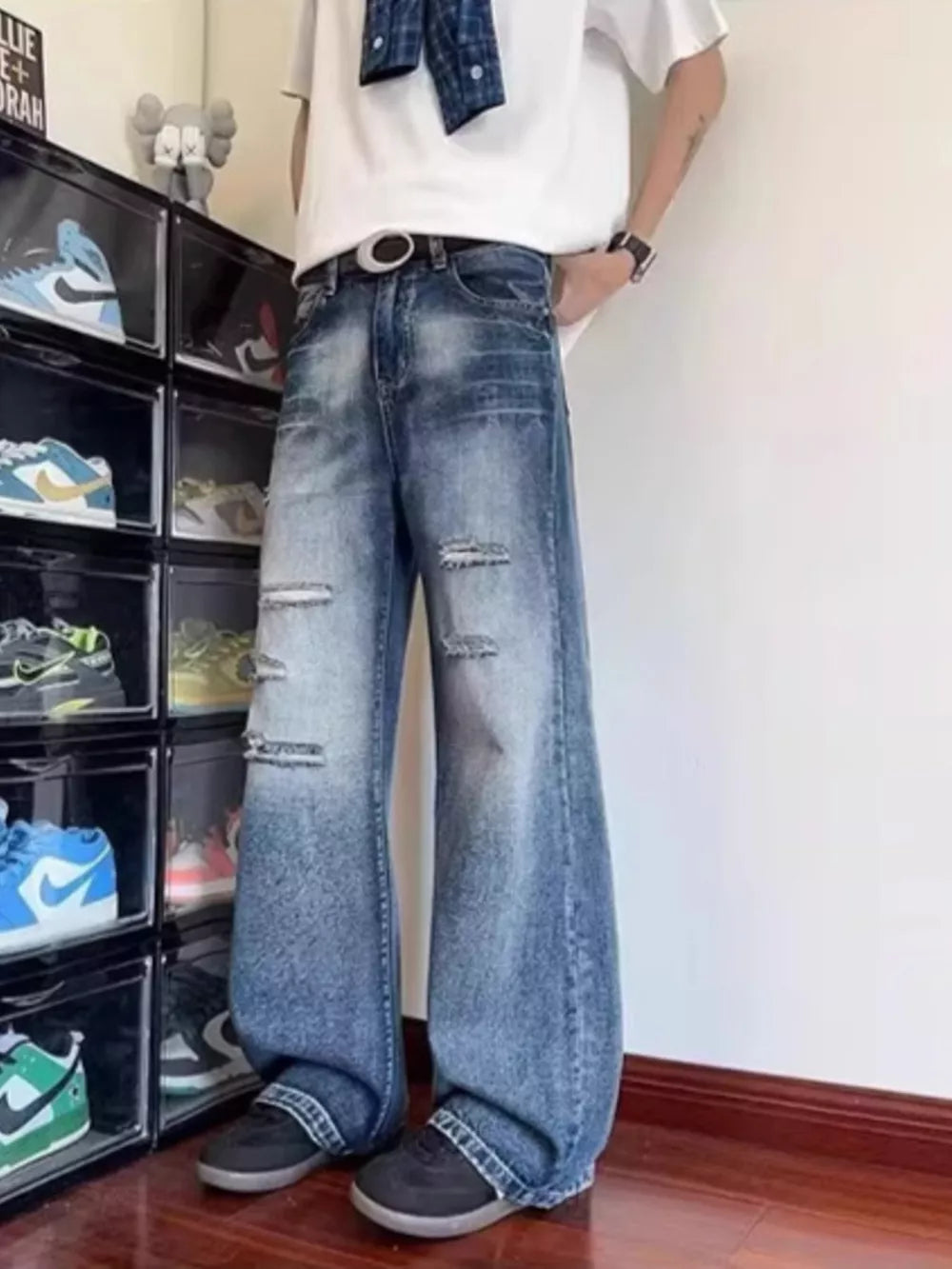 Distressed wide-leg men's jeans in blue denim with pockets and ankle pooling.