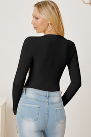 Black ribbed long sleeve bodysuit with plunge neckline, styled with light wash jeans.