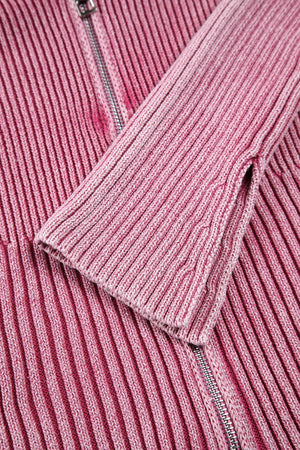 Pink ribbed knit top with flare sleeves and a zipper detail.