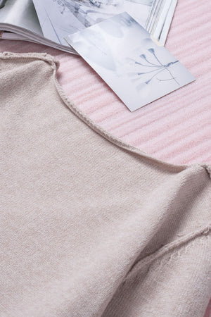 Off-the-shoulder knit sweater in eggshell with fringe trim detail.