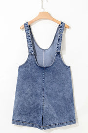 Acid wash denim romper with patch pockets and adjustable straps.