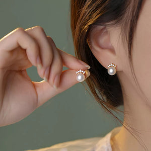 Pearl and zircon stud earrings with a crown design detail.