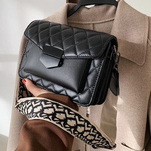 Chic quilted flap crossbody bag in black with a patterned strap and gold hardware.