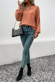 Raglan sleeve knit sweater in pumpkin acrylic with raw edge details and a V-neck.