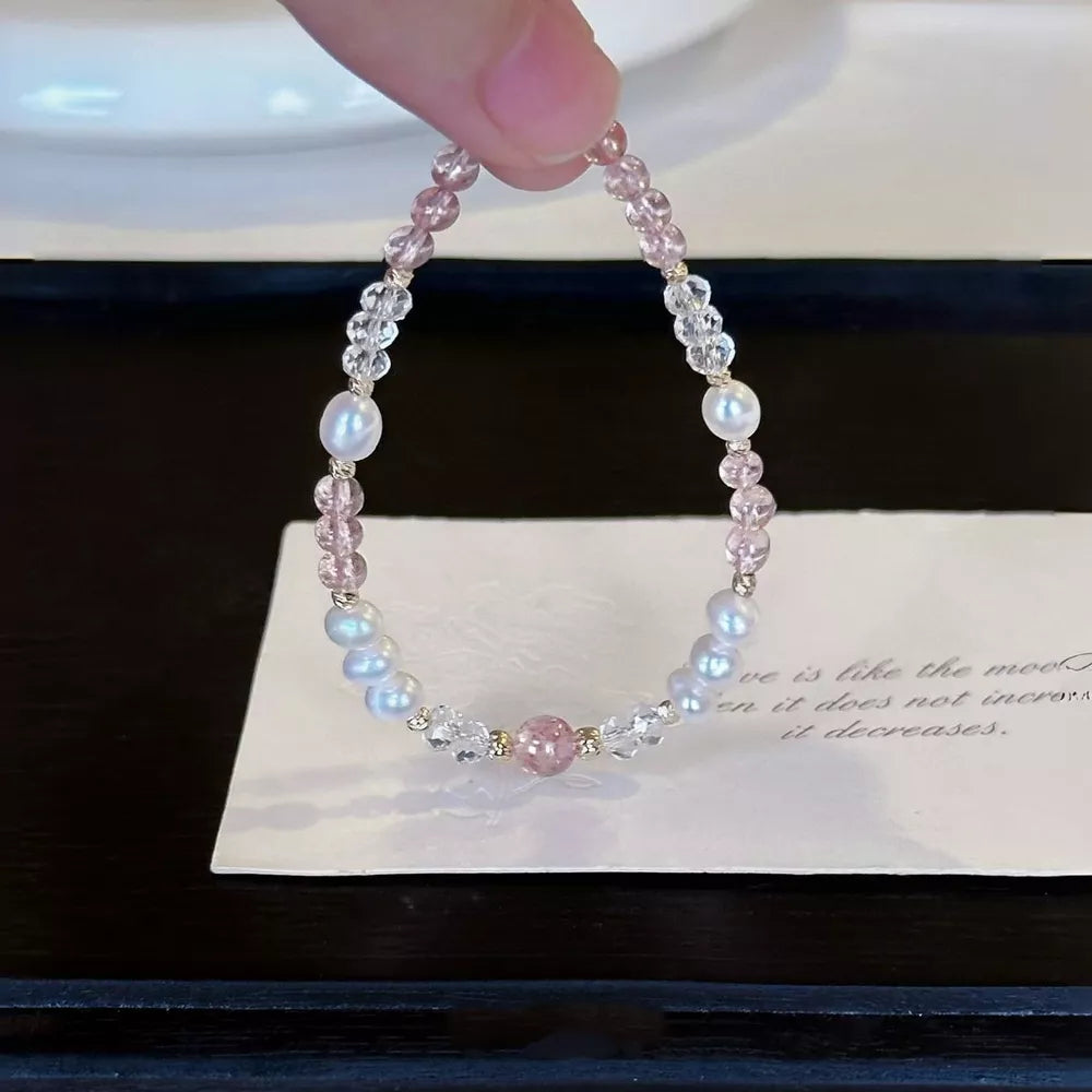 Delicate pearl and crystal bracelet with pink beads and a central pink stone.