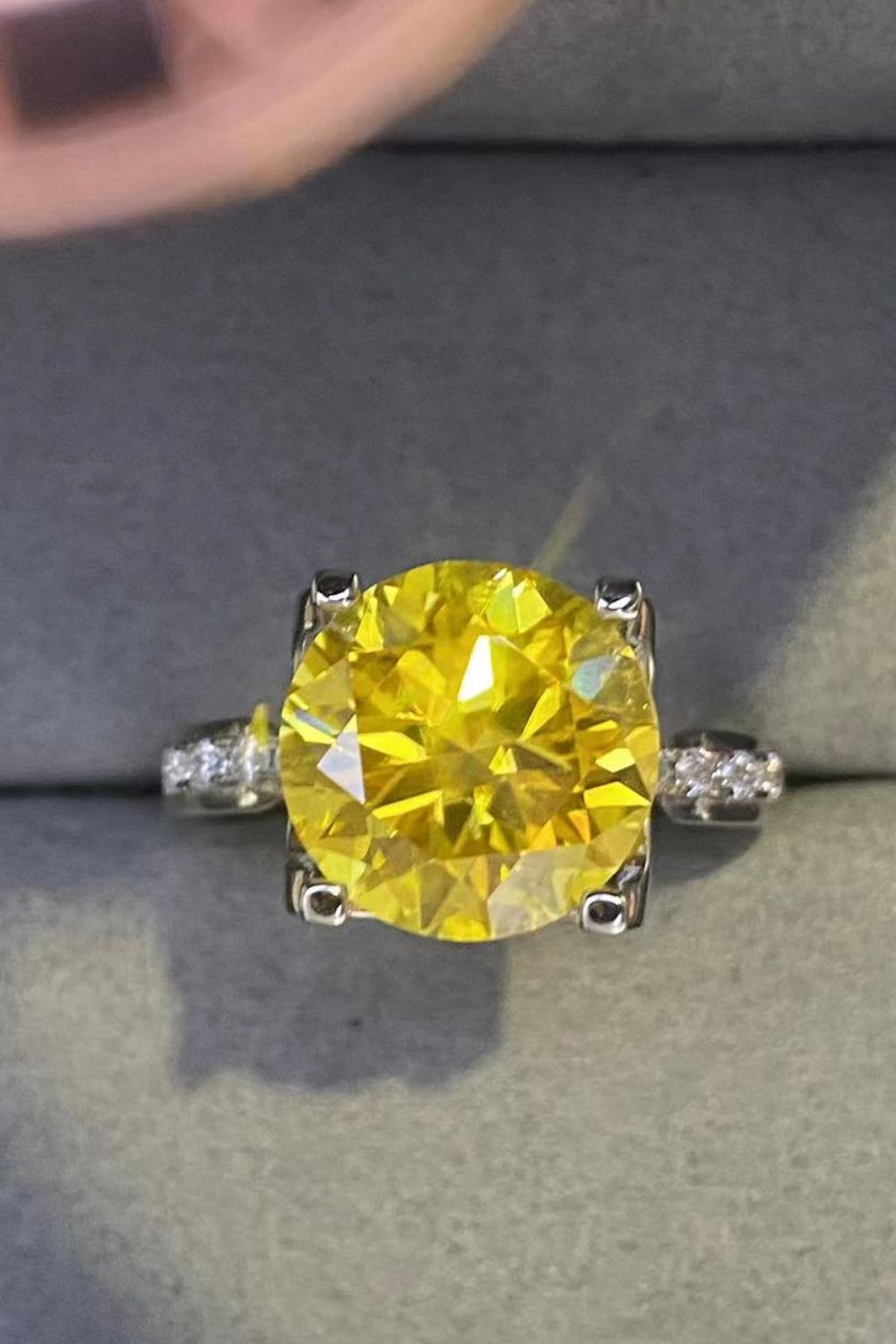 Silver solitaire ring with a bright yellow canary diamond and small accent stones.