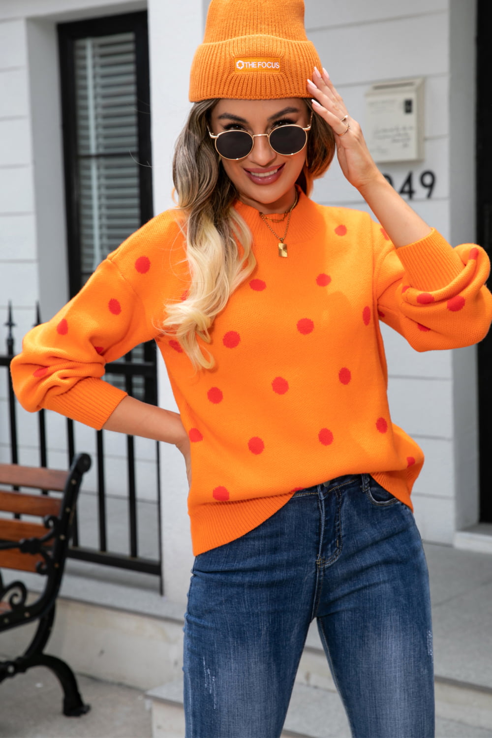 Orange polka dot knit sweater with balloon sleeves and mock neck, styled with jeans.