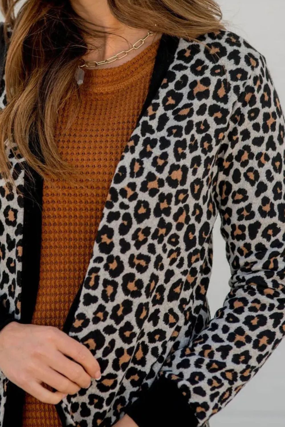 Leopard print open front cardigan with black contrast trim and cuffs.