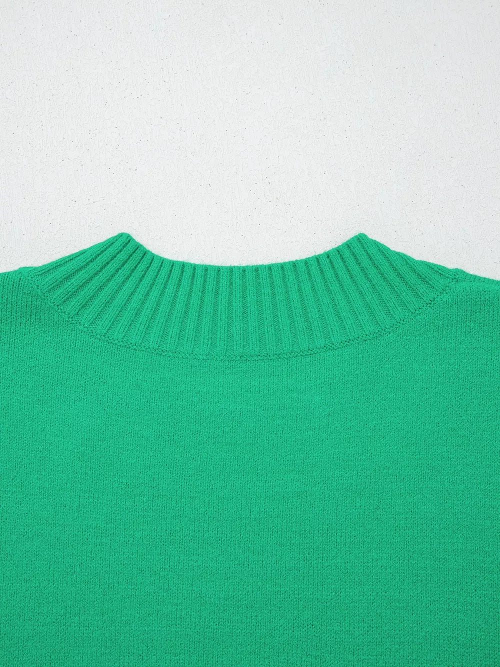 Green ribbed knit top with ruffled round neck and textured detail.