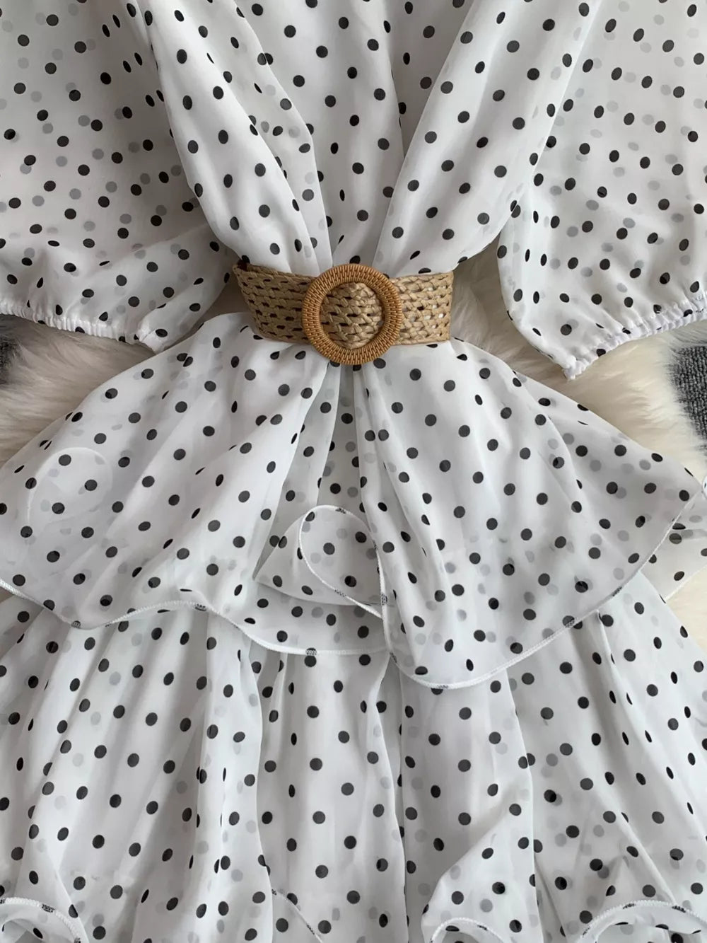 White polka dot tiered dress with a woven belt and ruffled details.