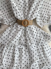 White polka dot tiered dress with a woven belt and ruffled details.