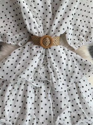 White polka dot tiered dress with a woven belt and ruffled details.