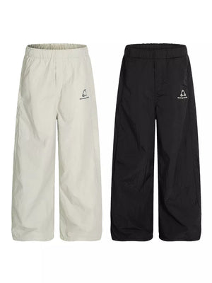 Men's wide-leg sweatpants in gray and black with crinkled texture and logo detail.