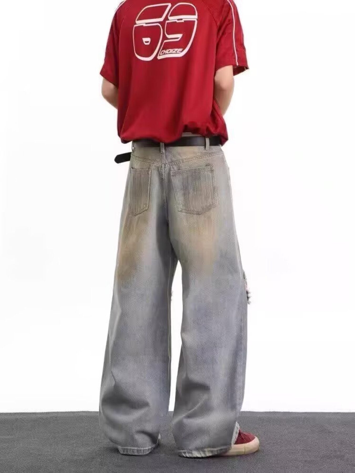 Men's distressed wide leg jeans in blue denim with artful fading and a ripped detail.