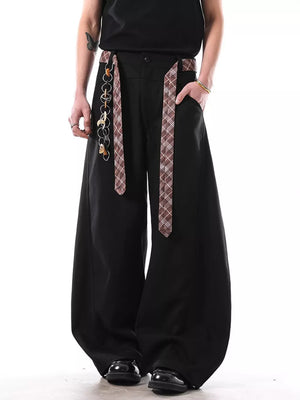 Black wide-leg sweatpants with plaid straps and chain detail.